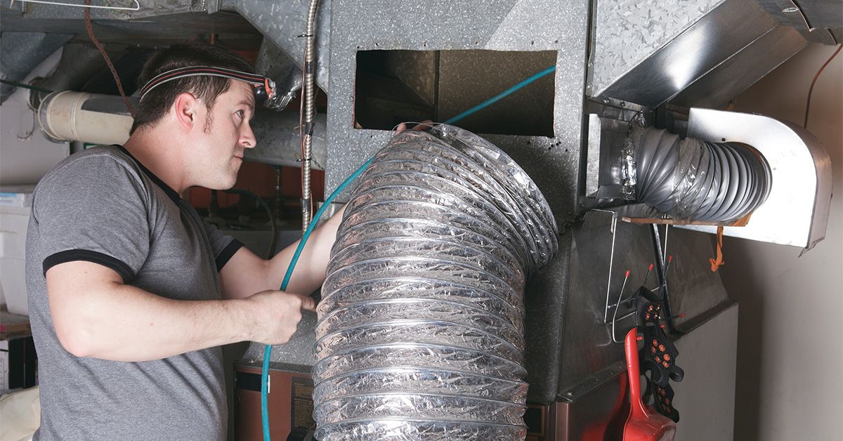 Technician inspecting HVAC duct system installation.